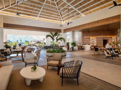 Otevřená hotelová lobby s moderním posezením a výhledem do venkovního prostoru.