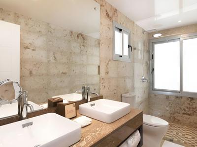 Moderne badkamer met hoekwasbakken, raam en vloertegels in warme tinten