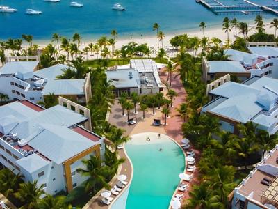 Luchtfoto van een resort met zwembad en zeezicht met jachten.