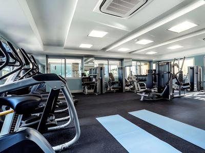 Heller Fitnessraum mit modernen Geräten und großen Fenstern mit Aussicht.