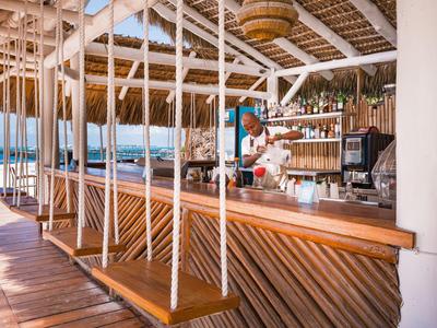 Area bar con altalene in legno e decorazioni tropicali in un hotel sulla spiaggia aperto.