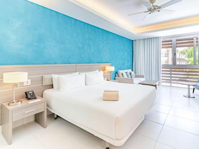 Camera d'hotel moderna con letto grande, parete blu e accesso alla terrazza.