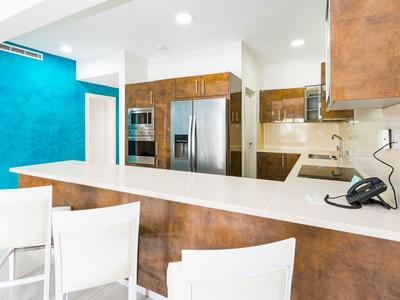 Area cucina moderna in hotel con sgabelli e elettrodomestici in acciaio inox dai toni caldi.