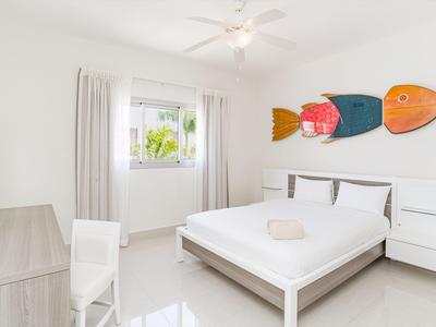 Camera d'hotel luminosa con letto matrimoniale, comodini e decorazioni murali colorate a forma di pesce.