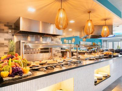 Buffet in un ristorante ben illuminato con frutta fresca e postazione di cucina.