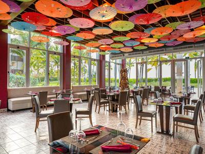 Una sala da pranzo luminosa con mobili in legno e ombrelli colorati sul soffitto.