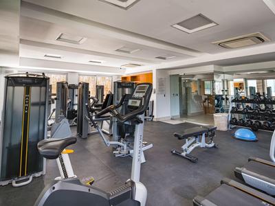Palestra moderna con macchine cardio, pesi e specchi in un hotel luminoso