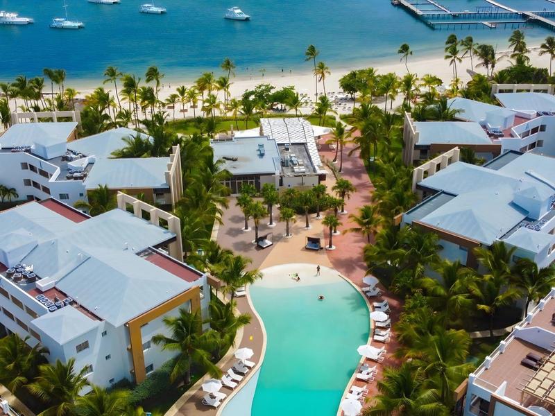 Luchtfoto van een resort met zwembad en zeezicht met jachten.