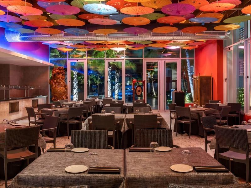 Modern restaurant met kleurrijke lantaarns aan het plafond en elegante tafels.