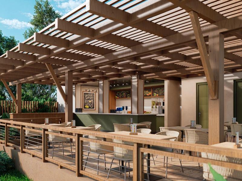 Buiten zitgedeelte met houten pergola, tafels, stoelen en een bar bij een resort.