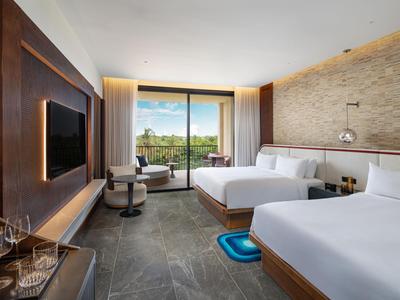 Modern ausgestattetes Hotelzimmer mit zwei Betten, Balkon und Blick auf die Natur.