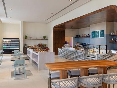 Modernes Café mit Holzdetails, hellen Farben und Sitzbereichen, ideal für eine entspannte Pause.