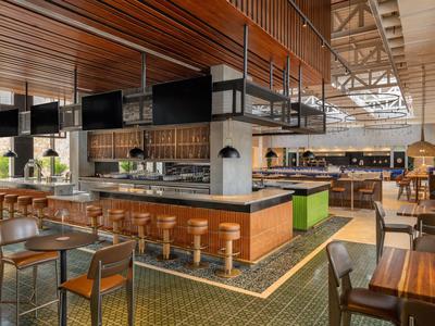 Modern eingerichtete Hotelbar mit Holz- und Ledermöbeln, Theke und viel natürlichem Licht.