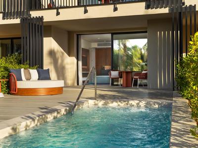 Moderner Hotelpool mit Liegesofa und offener Terrassentür zum Zimmer mit Naturblick.
