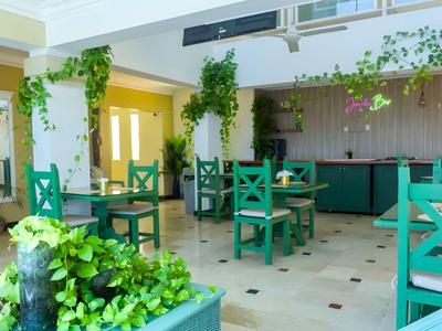 Sala colazione moderna e luminosa con sedie verdi e piante sospese in un hotel.