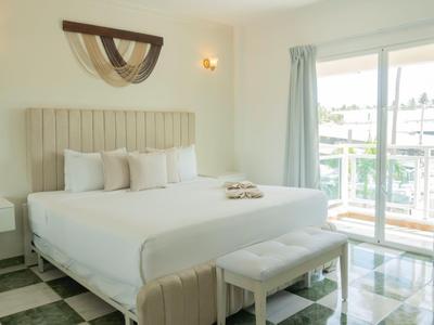 Camera d'hotel luminosa con letto king size, balcone e pavimento in piastrelle di marmo.