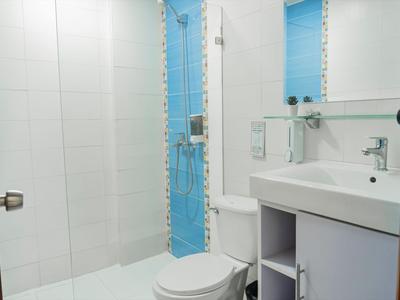 Bagno moderno con WC, lavabo e doccia in vetro con accenti blu.