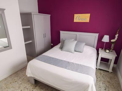 Piccola camera con letto bianco, parete grigia e arredamento minimale.