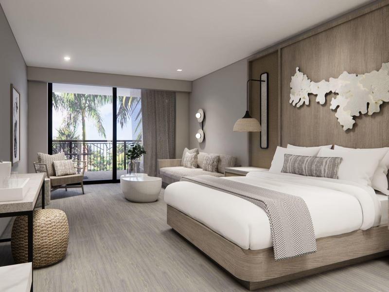 Nowoczesny pokój hotelowy z dużym łóżkiem, miejscem do siedzenia i balkonem z widokiem na palmy.