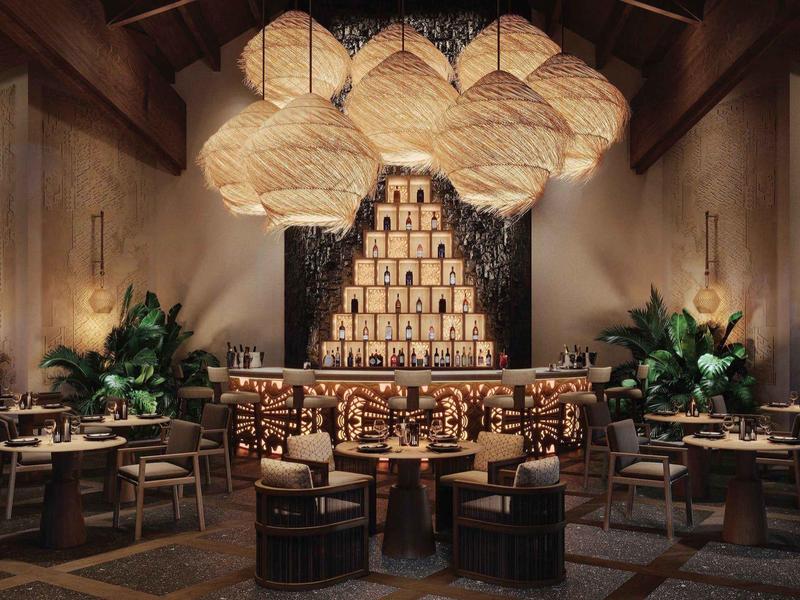 Elegancka restauracja z drewnianymi stołami, krzesłami i dużymi abażurami zawieszonymi pod sufitem.