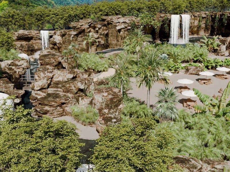 Tropikalny obszar basenu z wodospadami, piaszczystą plażą i parasolami, otoczony gęstą roślinnością.