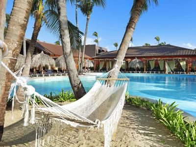 Amaca tra palme accanto a una piscina limpida in un resort tropicale.