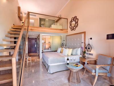Modern eingerichtetes Hotelzimmer mit Galerie, Sofa, Stuhl und Treppe aus Holz.