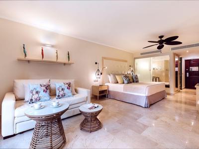 Modern eingerichtetes Hotelzimmer mit großem Bett, Sofa und Deckenventilator.