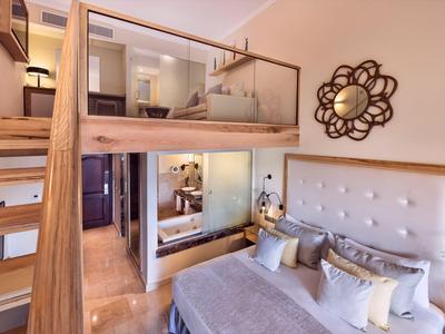 Modernes Hotelzimmer mit Etagenbett, Doppelbett, Holztreppe und dekorativer Wandgestaltung.