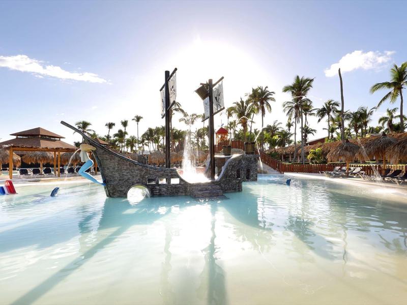 Piscina per bambini con nave pirata e palme in un resort alberghiero soleggiato