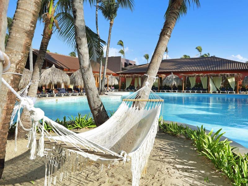 Amaca tra palme vicino alla piscina in un ambientazione di resort tropicale.