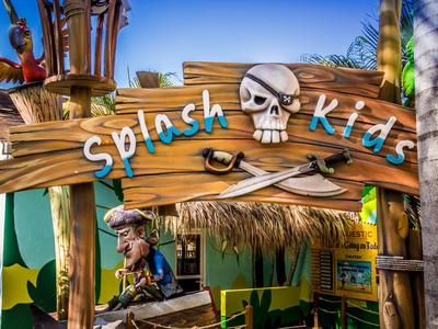 Dřevěná cedule s lebkou a zkříženými kostmi, nápis 'Splash kids' u vstupu.