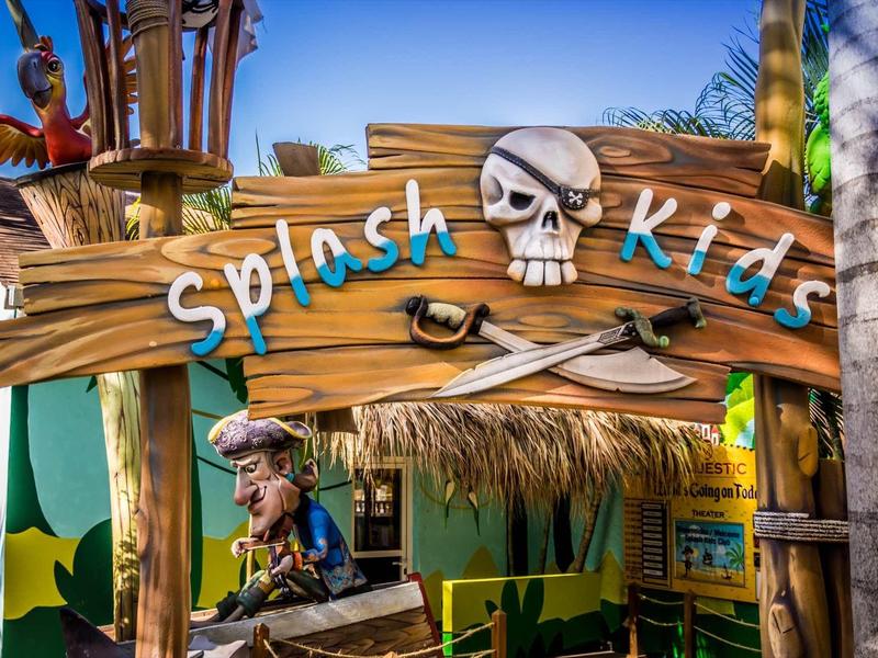 Dřevěná cedule s lebkou a zkříženými kostmi, nápis 'Splash kids' u vstupu.