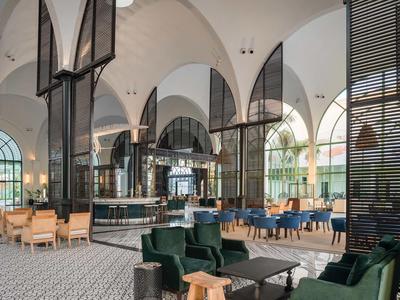 Elegancka przestrzeń lounge hotelu z wysokimi łukami, czarnymi kolumnami i różnokolorowymi miejscami do siedzenia.