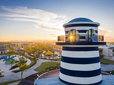 Latarnia morska w niebiesko-białe paski o zachodzie słońca w ośrodku hotelowym