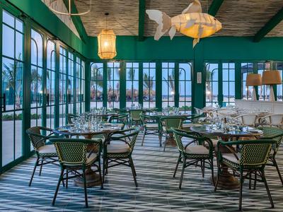 Elegantes Restaurant mit grün gestrichenen Wänden, Holzboden und gedämpfter Beleuchtung.
