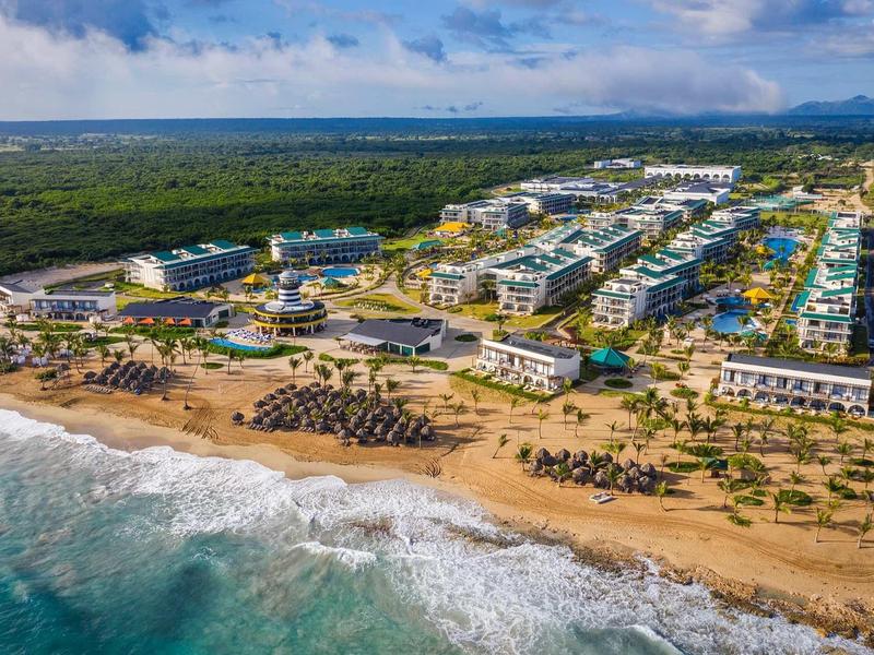 Luftaufnahme eines großen Strandresorts mit mehreren Gebäuden, Sandstrand und blauem Meer.
