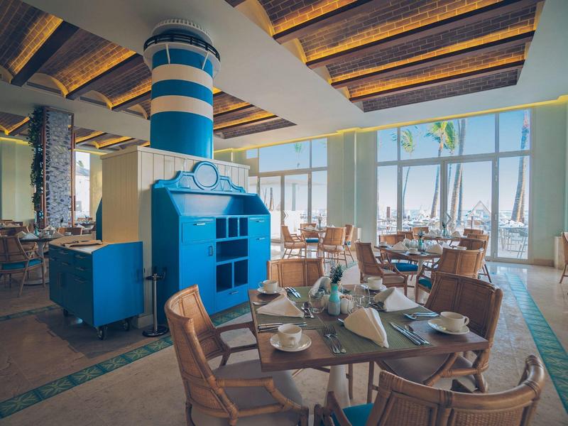 Modernes Restaurant mit Holzmöbeln, blauer Kamin, großen Fenstern und Tageslicht.