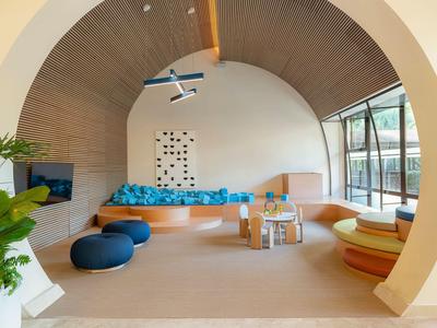 Modern hotel lobby area with curved wooden ceiling, blue cushions, and large windows.