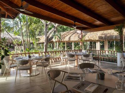 Open dining area with wooden roof, rattan chairs, and view of tropical garden