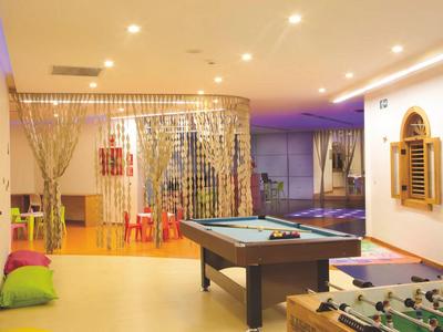 Moderní herna s kulečníkem, stolním fotbalem a polštáři v teple osvětlené místnosti.