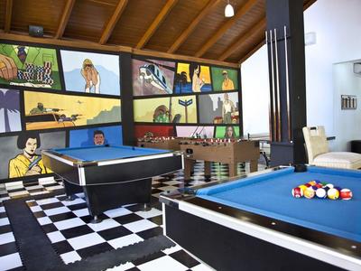 Místnost s kulečníkem, dřevěným stropem, barevnými nástěnnými malbami a černobílou šachovnicovou podlahou.