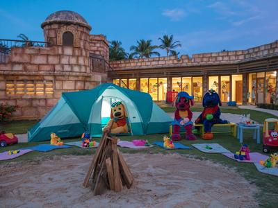 Children's play area with tent, toys, and two costumed puppets in front of a historic building.
