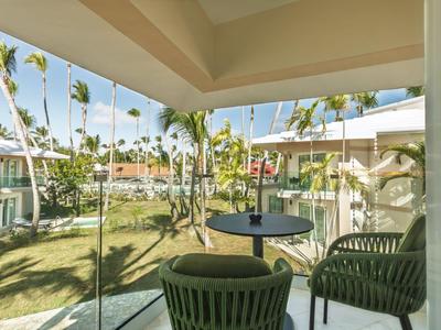 Balcony with chairs and table overlooking tropical garden and palm trees.