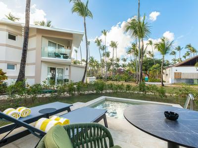 Modern hotel area with pool, lounge chairs, and palm trees in a tropical setting.