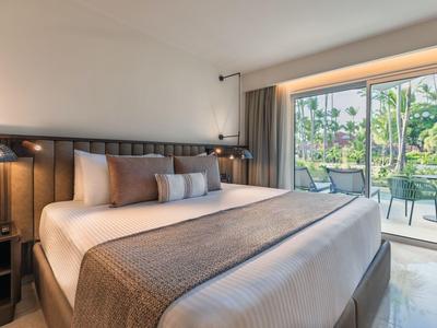 Modern hotel room with large bed and view of terrace and garden