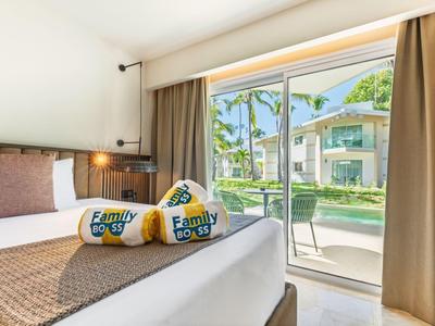 Hotel room with large bed and view of balcony and tropical garden.