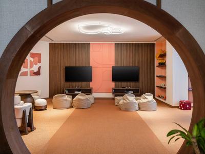 Modern play area with bean bags and two screens in a hotel.