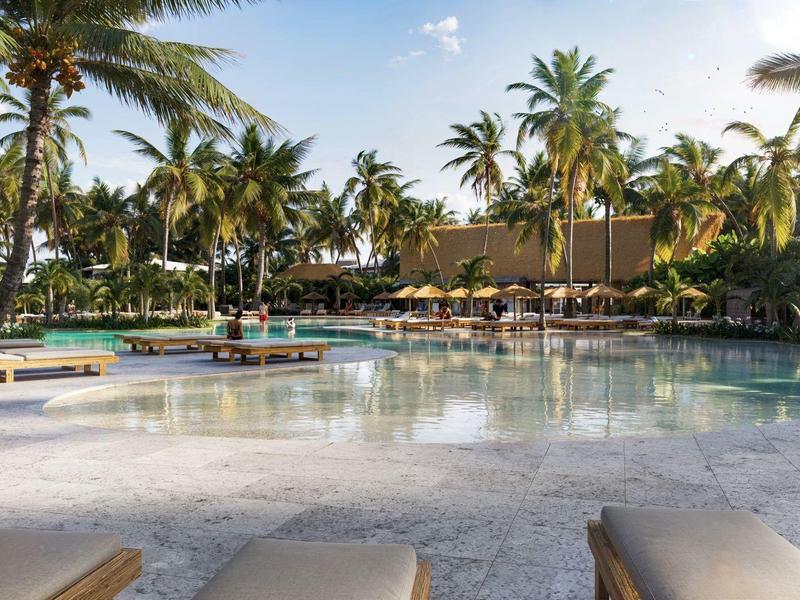 Velký hotelový bazén s palmami a lehátky za slunečného počasí