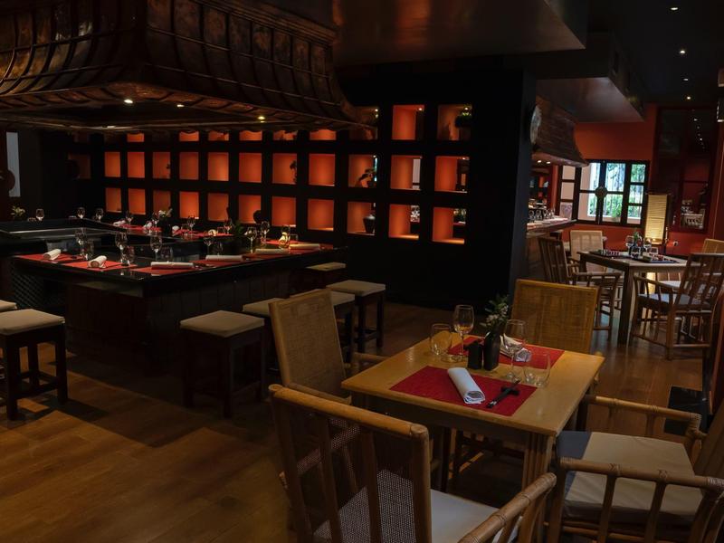 Temná, útulná restaurace se dřevěnými stoly, židlemi a jemným osvětlením.